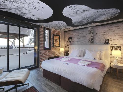 a bedroom with a large bed with white sheets at Snow Lodge Hotel Courchevel 1850 in Courchevel