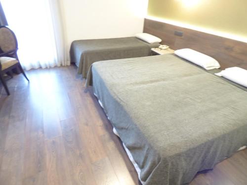 two beds in a room with wooden floors at Moderno in Barcelona
