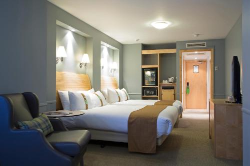 a hotel room with a large bed and a chair at Holiday Inn Guildford by IHG in Guildford