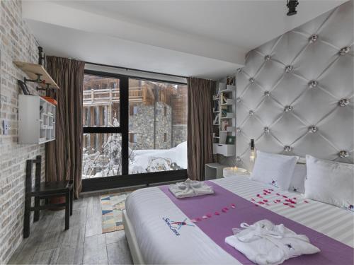 a bedroom with a large bed and a large window at Snow Lodge Hotel Courchevel 1850 in Courchevel