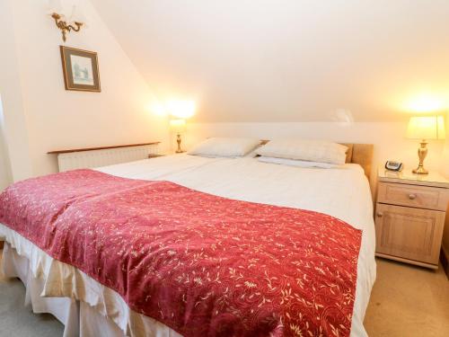 a bedroom with a large bed with a red blanket at Chestnut Apartment in Cheltenham