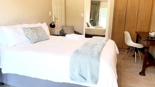 a bedroom with a white bed with a desk and a chair at Langa's Gabedi Goshen in Pretoria