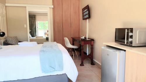 Habitación de hotel con cama, TV y escritorio. en Langa's Gabedi Goshen en Pretoria