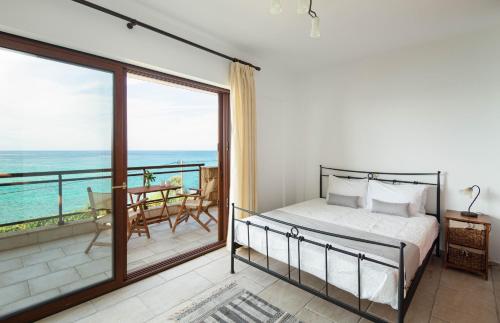 a bedroom with a bed and a balcony with the ocean at #FLH-Seagrove-Beachfront Villa In Possidi in Skála Foúrkas