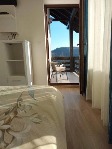 a bedroom with a bed and a balcony with a table at Pensiunea Agroturistica Acvila Apusenilor in Vadu Moţilor