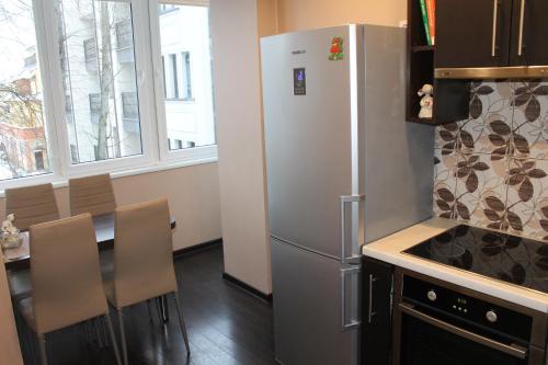 Il comprend une cuisine équipée d'un réfrigérateur et d'une table avec des chaises. dans l'établissement Apartamentai Flora, à Palanga