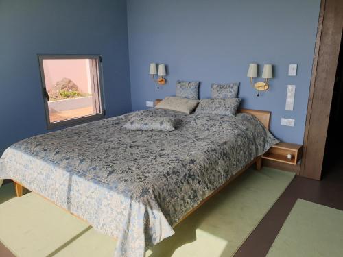 a blue bedroom with a bed and a window at Casa Atlantico Suite in Ribeira Brava