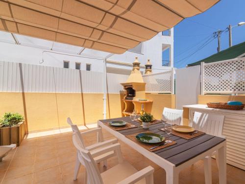 um pátio com uma mesa, cadeiras e um guarda-sol em Holiday Home Sunny Home by Interhome em Pêra