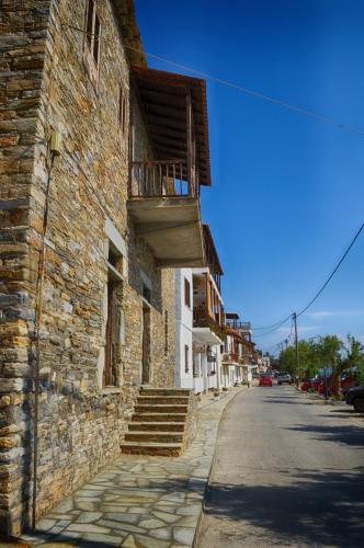 a stone building with a balcony on the side of a street at Guesthouse Irene in Afissos
