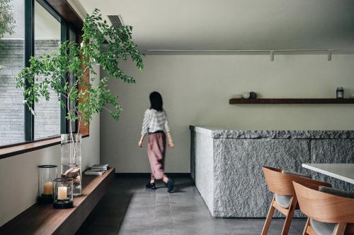 a woman walking in a room with a counter at Commune by the Great Wall, in the Unbound Collection by Hyatt in Yanqing