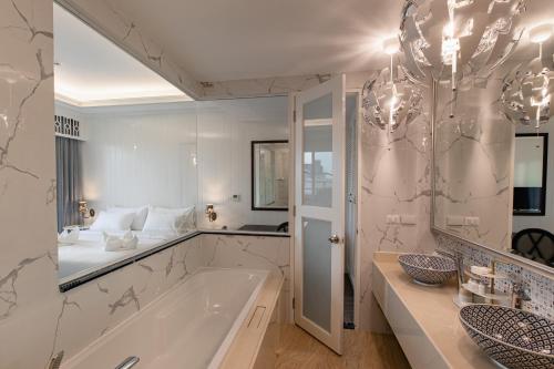 een badkamer met een bad en een grote spiegel bij Siam Tharadol SHA Extra Plus in Bangkok