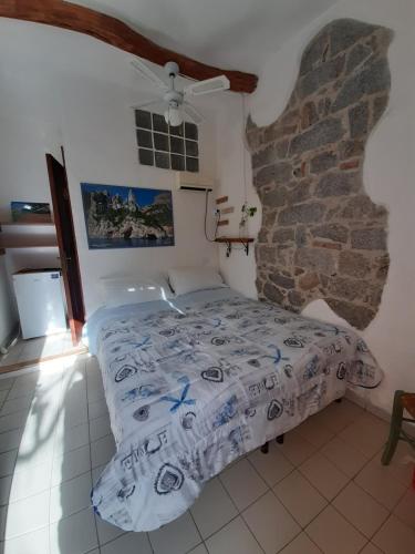 um quarto com uma cama e uma parede de pedra em S'Imbragu Farm B&B em Tortolì