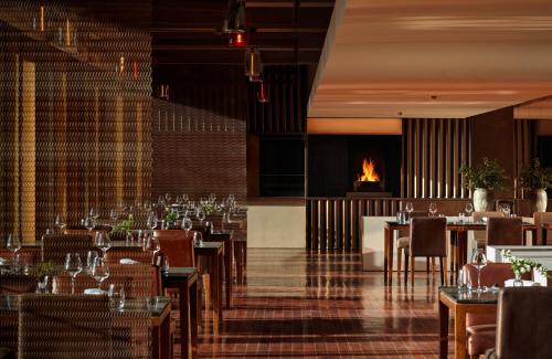 a restaurant with tables and chairs and a fireplace at Commune by the Great Wall, in the Unbound Collection by Hyatt in Yanqing