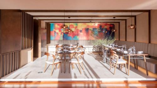 a dining room with tables and chairs and a painting at Commune by the Great Wall, in the Unbound Collection by Hyatt in Yanqing