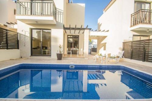 a swimming pool in front of a house at Protaras Allium Villa in Protaras