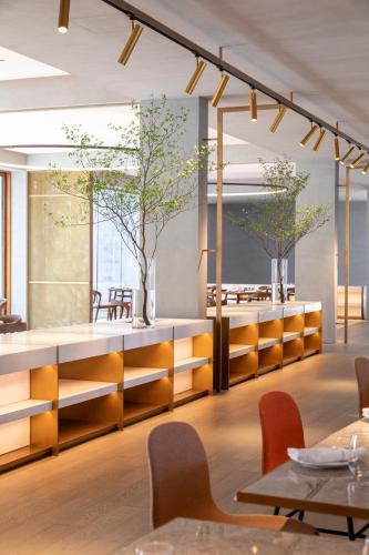 a dining room with tables and chairs and trees at Commune by the Great Wall, in the Unbound Collection by Hyatt in Yanqing