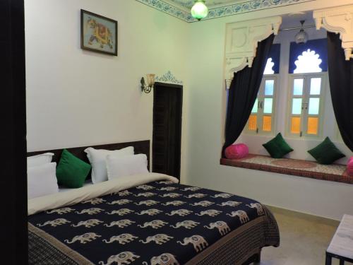 a bedroom with a bed and two windows at Hotel Ushaan Haveli in Udaipur