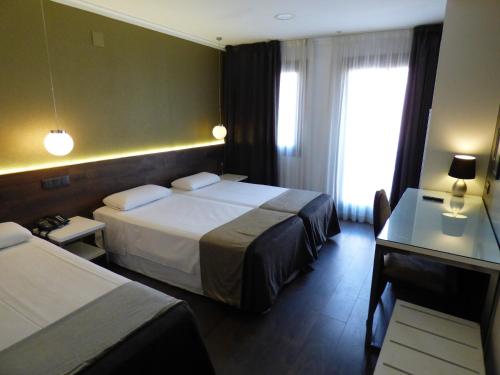 a hotel room with two beds and a desk at Moderno in Barcelona
