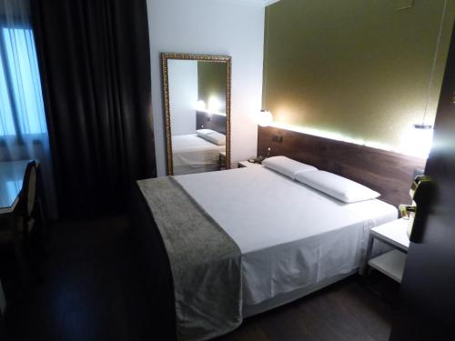 a bedroom with a large white bed and a mirror at Moderno in Barcelona
