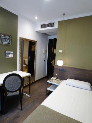 a room with two beds and a table and a chair at Moderno in Barcelona