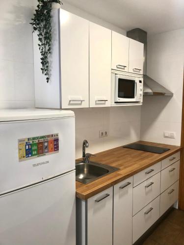 a white kitchen with a sink and a microwave at Estudios en la playa in Valencia