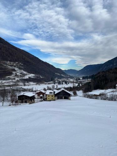 a snow covered field with buildings in the mountains at Casa Penasa Appartamento 1 in Commezzadura