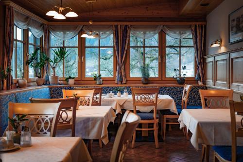a restaurant with tables and chairs and windows at Pension Glitschnerhof in Aigen im Ennstal
