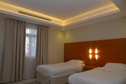 a hotel room with two beds and a window at بيوت عطلات التلال الفاخرة للايؤاء السياحي altelal alfakhra holiday homes in Taif