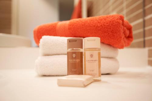 - un tas de serviettes et une bouteille de savon sur un comptoir de salle de bains dans l'établissement PALAIS LIBERTE, à Nice