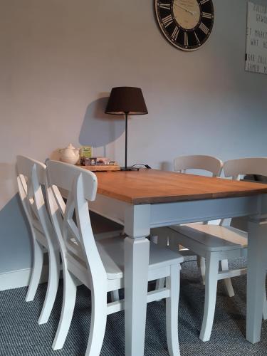 einen Esstisch mit Stühlen und eine Uhr an der Wand in der Unterkunft Vakantiehuis aan het Bos - langs de Tulpenroute! in Bant