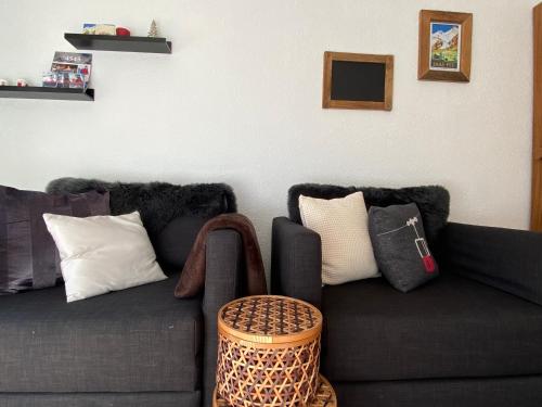 een woonkamer met een zwarte bank met kussens bij Haus Alpalin - 2 adjacent studios 'Mischabel', cosy, central, 4p in Saas-Fee