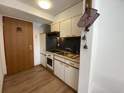 een kleine keuken met een wastafel en een deur bij Haus Alpalin - 2 adjacent studios 'Mischabel', cosy, central, 4p in Saas-Fee