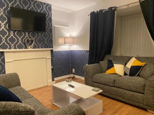 a living room with two couches and a tv at Cosy 3 Bedroom house, Free parking & WIFI in Nottingham