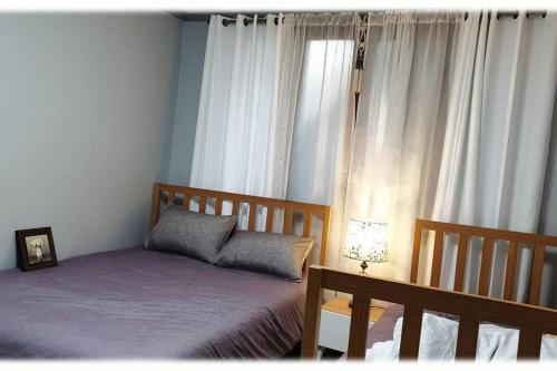 1 dormitorio con 2 camas y una ventana con cortinas en House that only walks on flowery paths, en Wonju