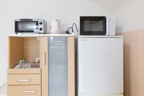 a microwave and a refrigerator in a kitchen at Simple Stay Beppu in Beppu