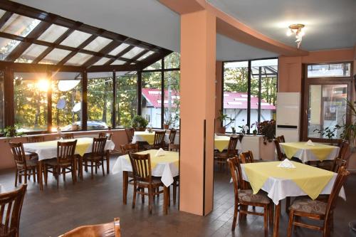 a restaurant with tables and chairs and windows at Хотел Сима in Beklemeto
