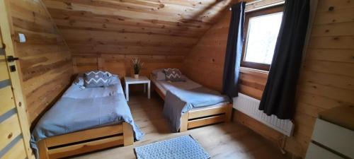 a room with two beds in a log cabin at ZACISZE Domek na Kaszubach Brodnica Dolna z balią z jacuzzi in Brodnica Dolna