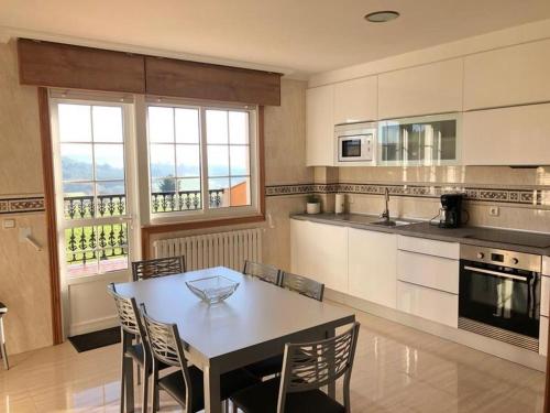 a kitchen with a table and chairs and a kitchen withwindows at Casa Abeleira in Arzúa