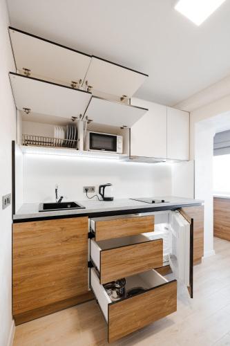 a kitchen with white walls and wooden drawers at CityApartments Kyiv Obolon in Kyiv