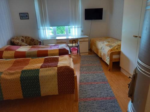 a hotel room with two beds and a television at Opintola Bed & Breakfast in Norinkylä