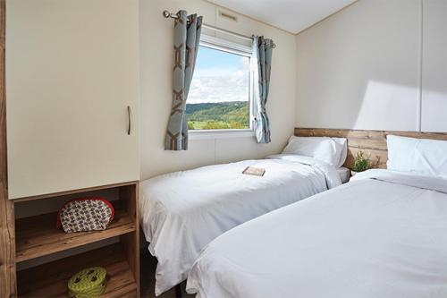 a bedroom with two beds and a window at Moffat Manor Holiday Park in Beattock