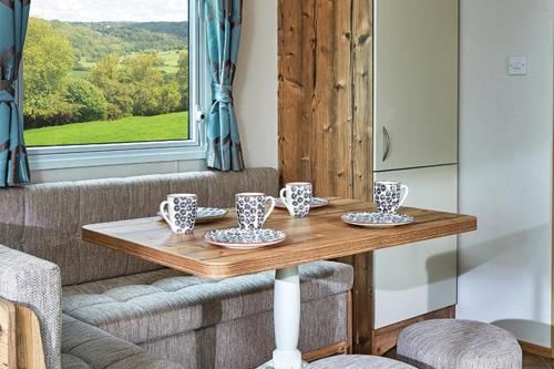 a wooden table with cups and saucers on it at Moffat Manor Holiday Park in Beattock