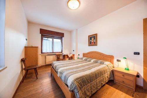 1 dormitorio con cama, mesa y ventana en La pratolina piano terra, en Castello di Fiemme