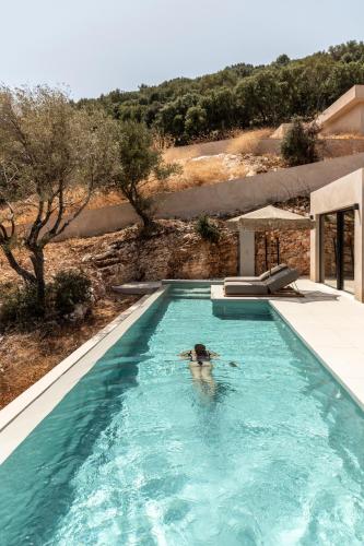 a person is swimming in a swimming pool at Pera Perou unspoiled luxury villas in Ayia Evfimia