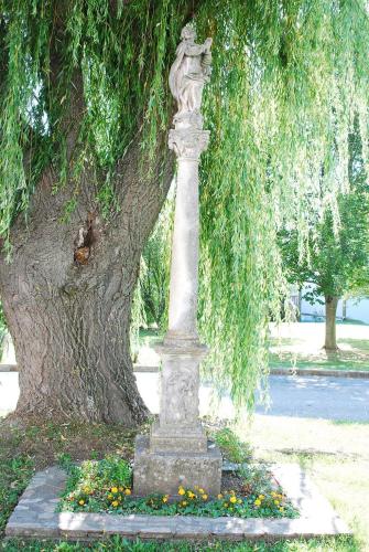 a statue in front of a tree with flowers at Pfarrschlössl Sallapulka in Purgstall