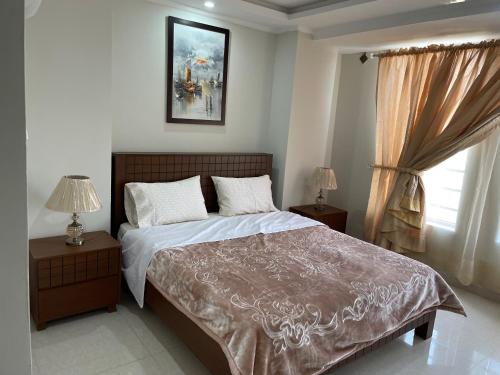 a bedroom with a bed and two night stands and a window at Marine Tower in Rawalpindi