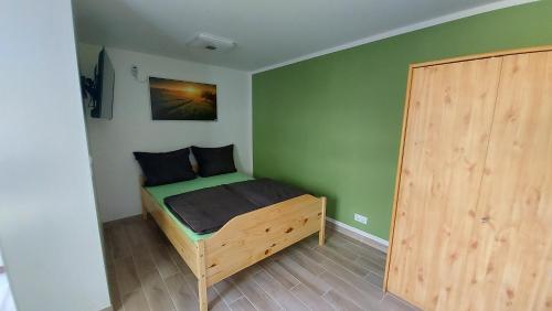 um pequeno quarto com uma cama e uma porta de madeira em Ferienwohnung Hase und Igel em Sundhagen-Niederhof