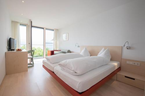 a white bedroom with a large bed with white pillows at Hotel Seegasthof Oberndorfer in Attersee am Attersee