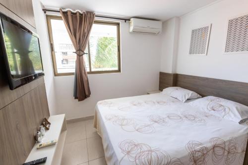 a bedroom with a bed and a window and a television at PÉ NA AREIA - 2 qt - 2 WC - PISCINA - wifi - garagem privativa in João Pessoa