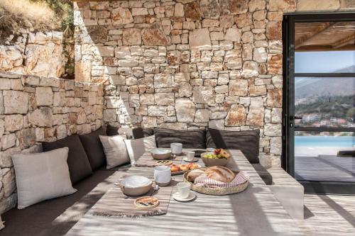 a table with food on it in front of a stone wall at Pera Perou unspoiled luxury villas in Ayia Evfimia